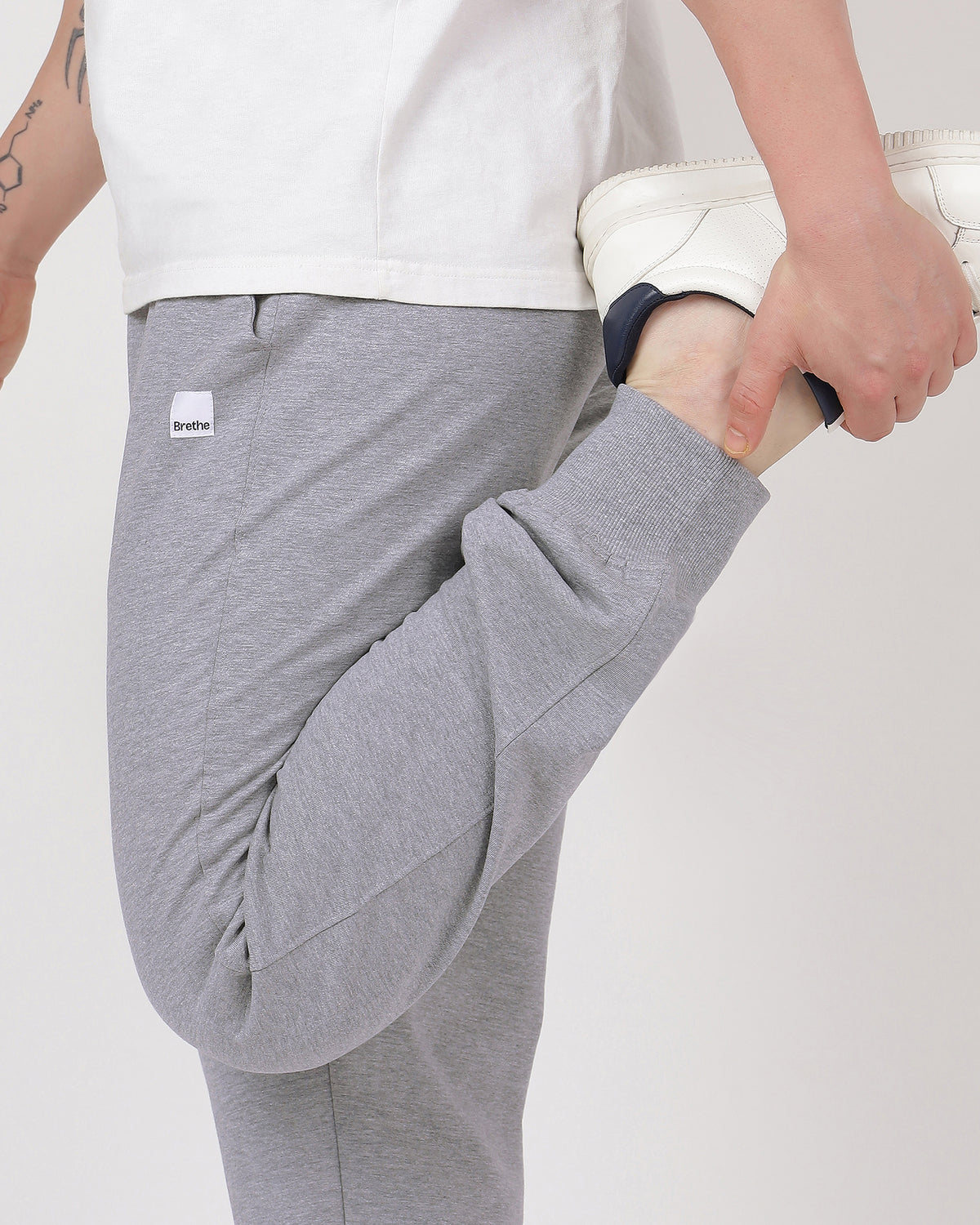 Close-up of Brethe Heather Grey joggers showing the fabric texture and relaxed fit during a standing quad stretch.